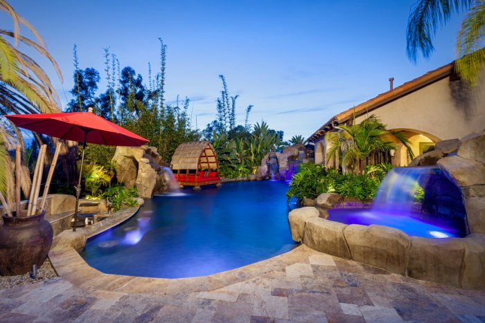 Custom Bali-style outdoor pool. Custom Bali-style outdoor pool with multiple waterfalls, in-pool lighting, spa, cave, Balinese pavilion and tropical landscaping.